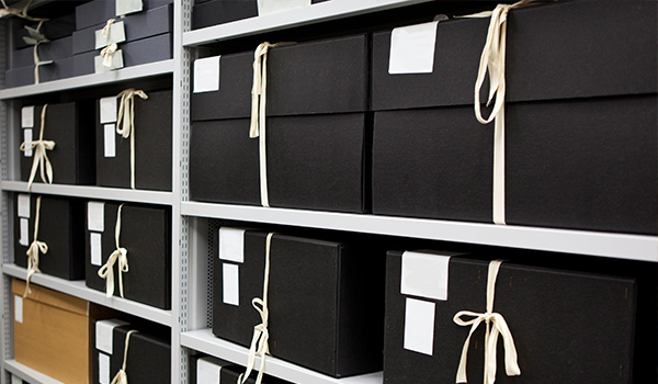 black storage boxes organized on shelves with labels and ribbons for easy access to documents and items eight boxes in a row