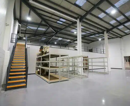 interior of a spacious industrial facility featuring a staircase and shelving units ideal for 13 storage solutions and organization