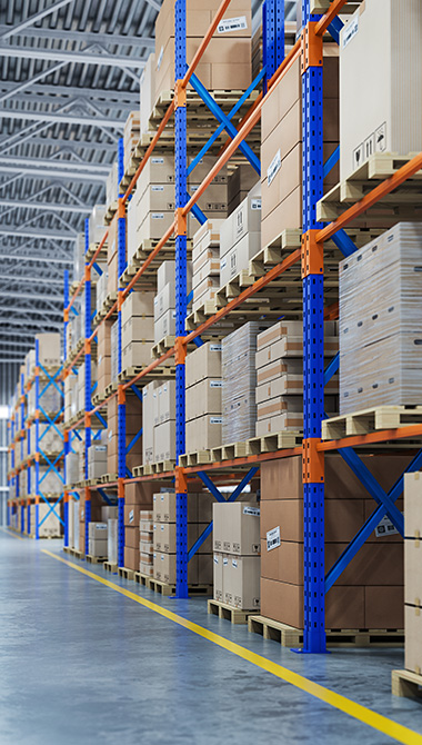 warehouse interior featuring multiple shelves filled with stacked cardboard boxes including seven stacks visible in the image