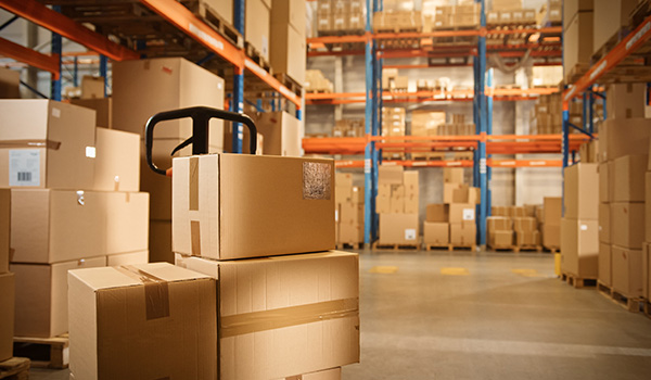 warehouse with stacked cardboard boxes and a pallet jack in front showing efficient storage solutions for five types of products