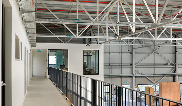 view of a modern industrial corridor with a balcony and large windows showcasing a spacious interior six lighting fixtures and an open design