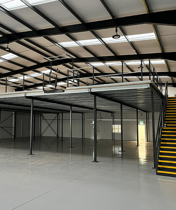 industrial space with a mezzanine level and yellow stairs showcasing a spacious and open layout suitable for 3 different uses such as storage or office space